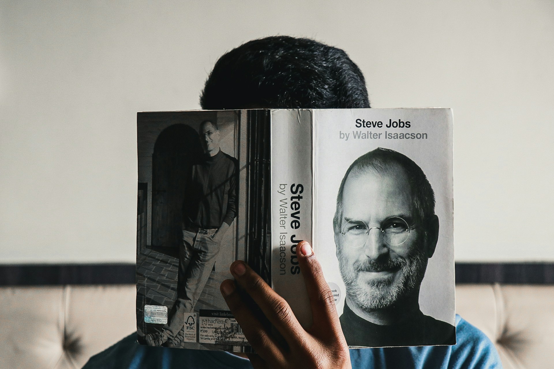 Čitateľ drží otvorenú biografiu Steva Jobsa.